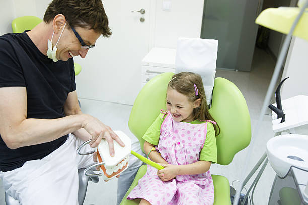 istock Girl in dentists chair tooth-brushing a model 483474714
