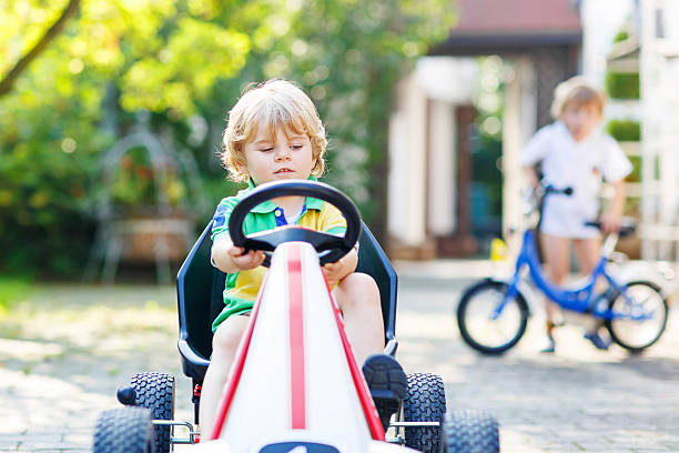 istock Active little boy driving pedal car in summer garden 483476482