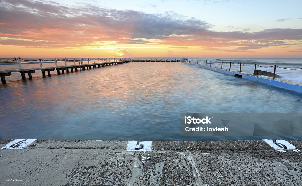 Sunrise Swim North Narrabeen Sunrise at the ocean fed swimming pools at North Narrabeen, Australia, known as the North Narrabeen Rock Baths with its distinctive boardwalk (left) to another 50m diving platform Australia Stock Photo