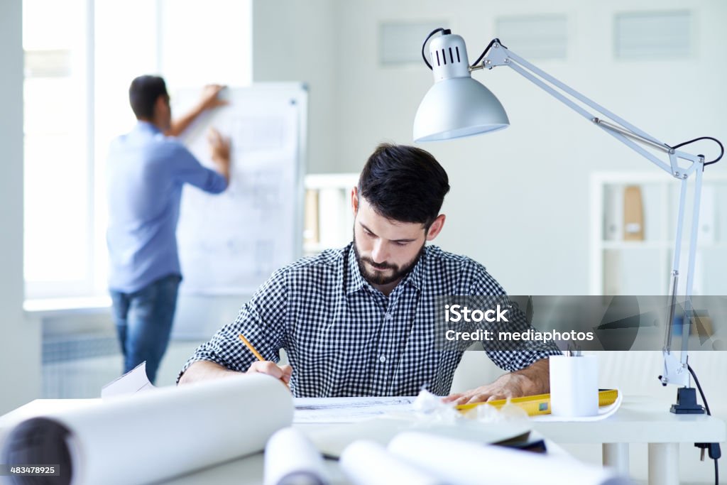 Working up to his ears Busy architect working on plan at office 20-29 Years Stock Photo