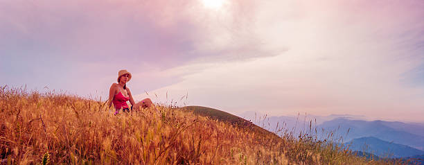 Young woman sitting on a hill stock photo