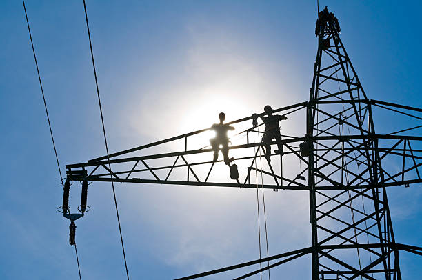 istock Linemen on a power pylon, bue sky and sun 483485472