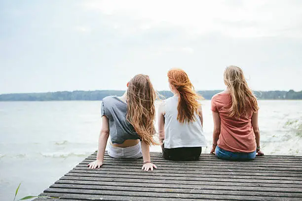 Photo of rear view of three teenage girls with blowing long hair