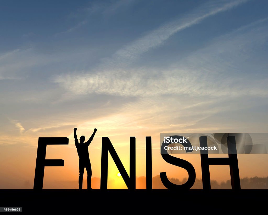 Finish silhouette The finish win is silhouetted against an orange and blue sunset. The I in the word is made from a figure with their arms raised up in the air in a successful victory pose. Finishing Stock Photo