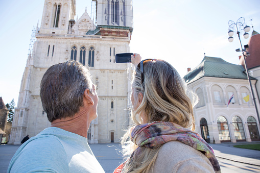 Couple take smart phone pic of cathedral, selfie, Zagreb, Croatia