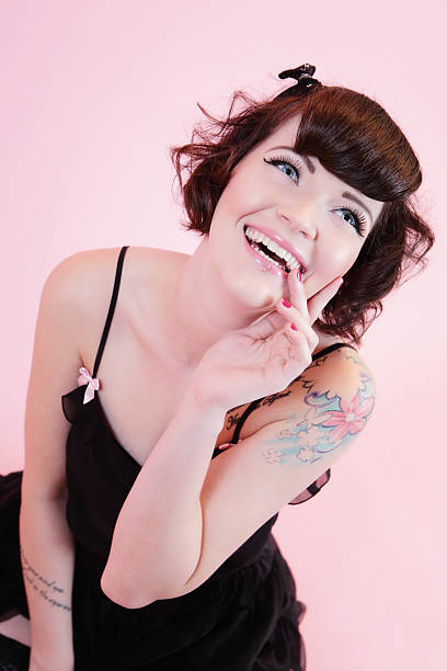 Happy Pinup style woman Happy Pinup style woman in black dress looking up and smiling. black pin up girl tattoos stock pictures, royalty-free photos & images