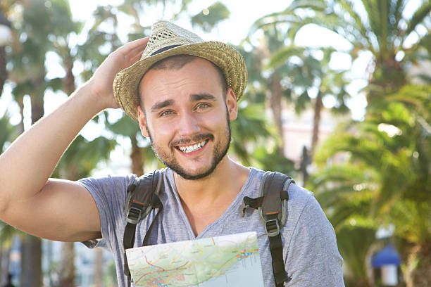 istock Happy guy on vacation with bag and hat holding map 483500962