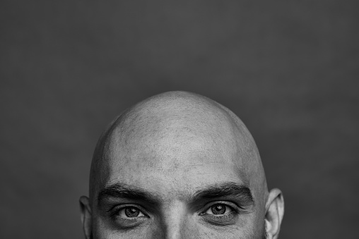 Cropped image of bald man looking at camera