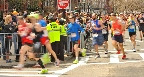 Boston, Mass., USA - April 15, 2013: Boston marathoners passing Boston Police officers on the corner of Hereford St. & Commonwealth Ave. just 2 blocks away and moments before the second of two bombs exploded on Boyleston St.