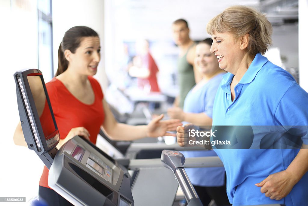 Treadmill workout. Senior woman having a treadmil cardio workout with instructor assistance. Fun and healthy. Gym Stock Photo