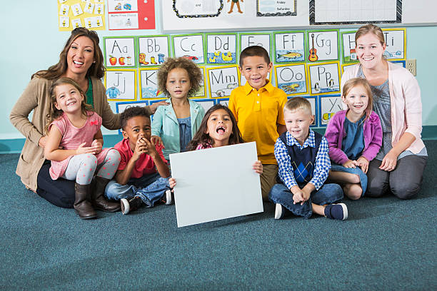 istock Kindergarten class with child holding blank sign 483506458