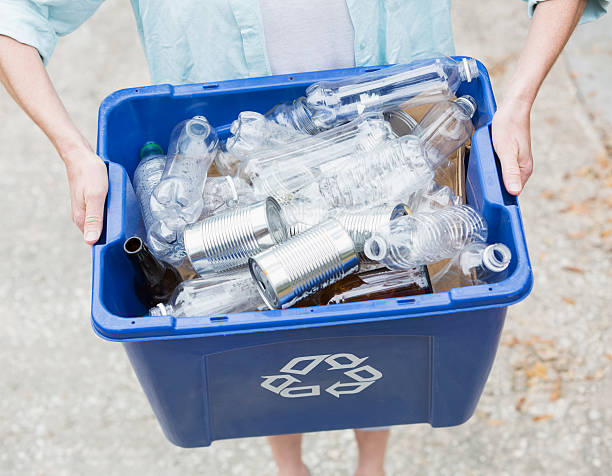 Cropped view of mature woman (40s) taking recycling bin out to the curb for collection.