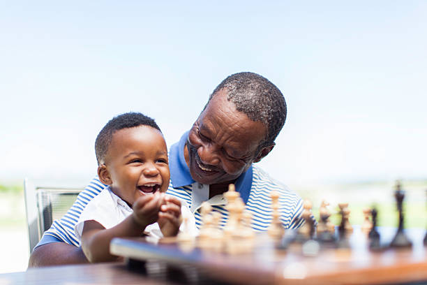 African grandfather playing chess with his grandson stock photo