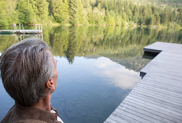 istock Man stands on pier, looks across lake 483507746