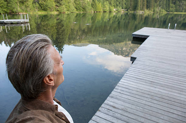 istock Man stands on pier, looks across lake 483507790