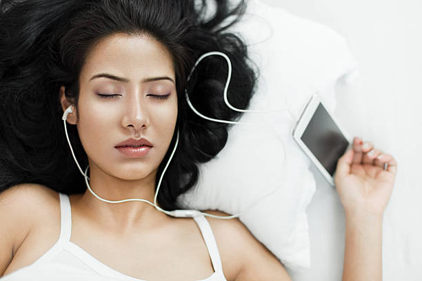 young woman sleeping with smart phone and headphones on. - spaghettibandjes stockfoto's en -beelden