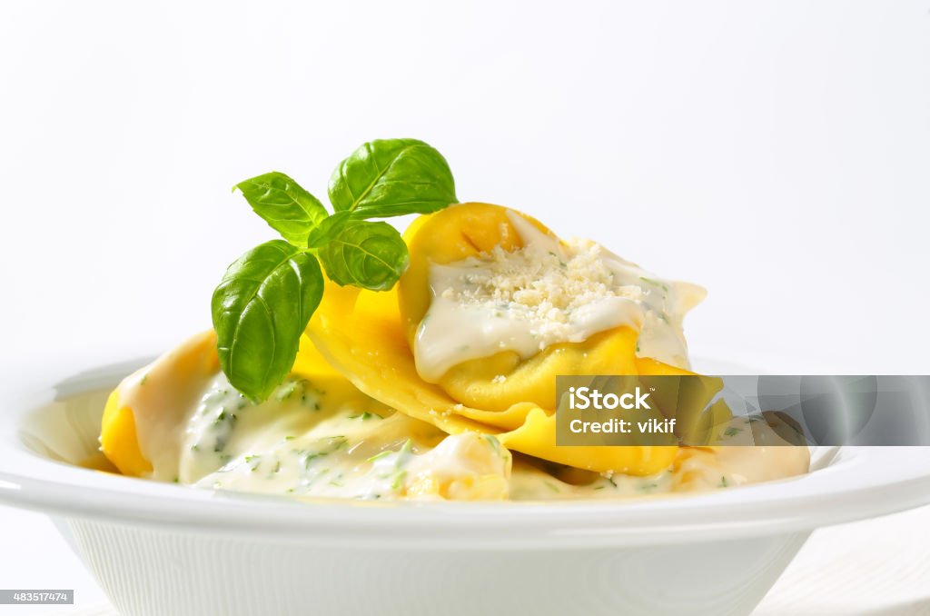 Ricotta and spinach tortelloni with cream sauce Spinach and ricotta stuffed pasta served with white cream sauce and grated Parmigiano 2015 Stock Photo