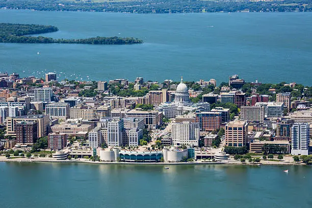 An aerial shot of the strip of Madison Wisconsin's downtown showing both the Monona Terrace and Capitol buildings as well as Picnic Point in the far background. Also shows parts of both Lakes Monona and Mendota. 