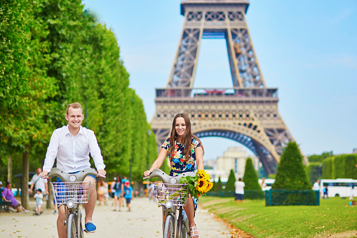 Young romantic couple of tourists using bicycles near the Eiffel tower in Paris, France