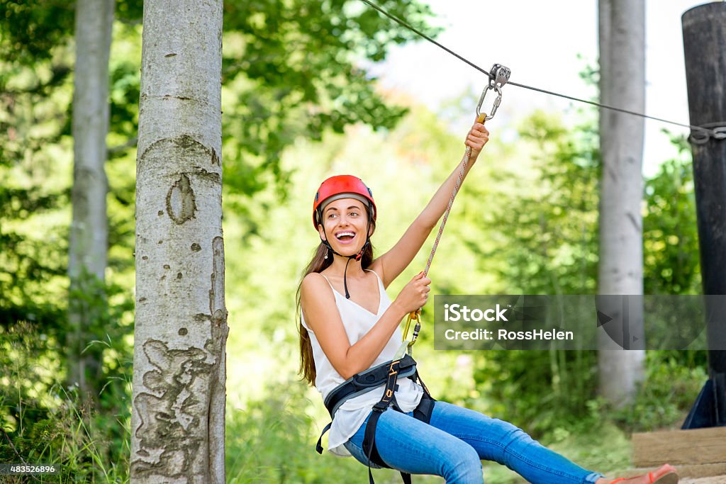 Woman riding on a zip line Young and pretty woman in red helmet riding on a zip line in the forest. Active sports kind of recreation Zip Line Stock Photo