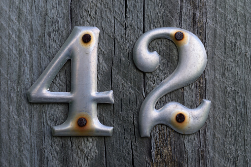 Metal Number 42 Nailed to Weathered Wood Post