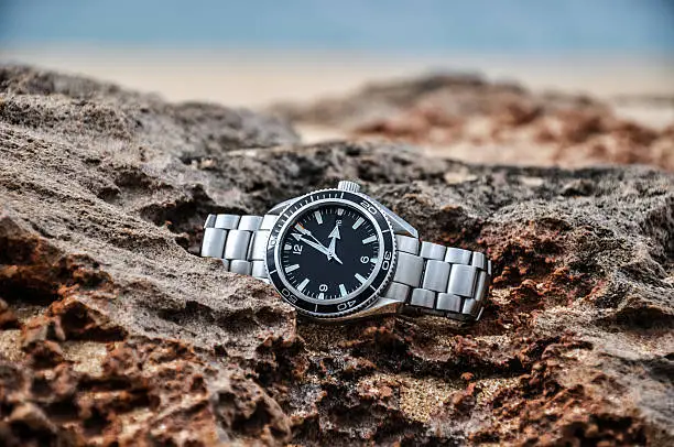 A beautiful swiss wrist watch lying on a rock. Markings removed.