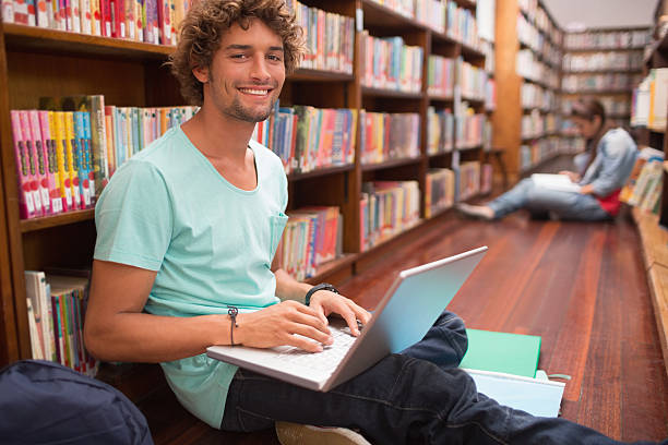 istock Student with laptop sitting on floor in library 483529463