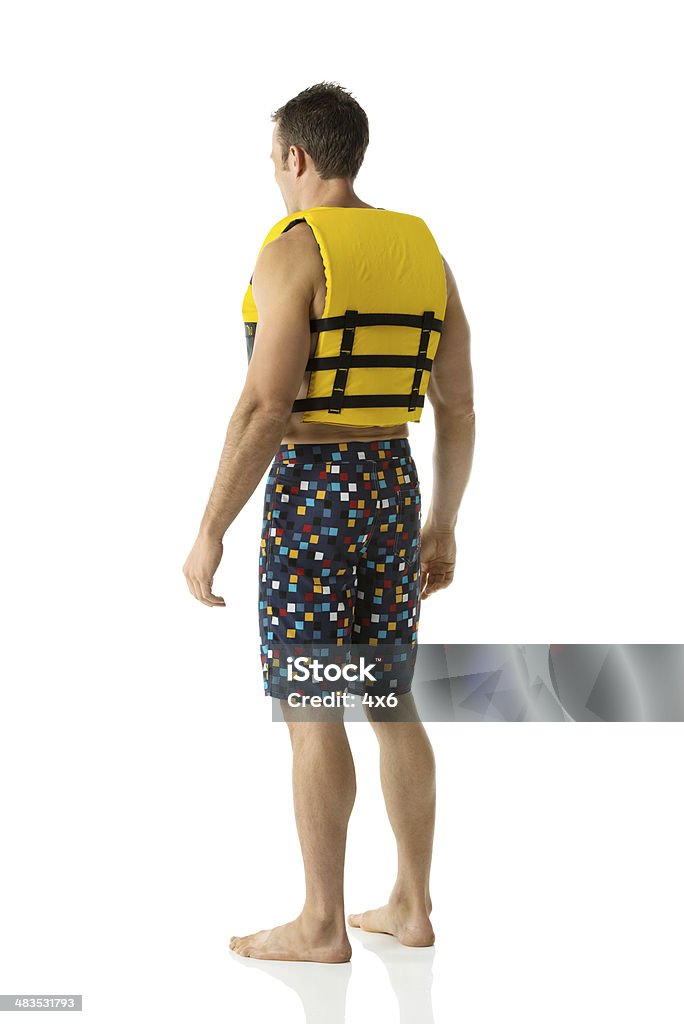 Rear view of man wearing life jacket Rear view of man wearing life jackethttp://www.twodozendesign.info/i/1.png Life Jacket Stock Photo