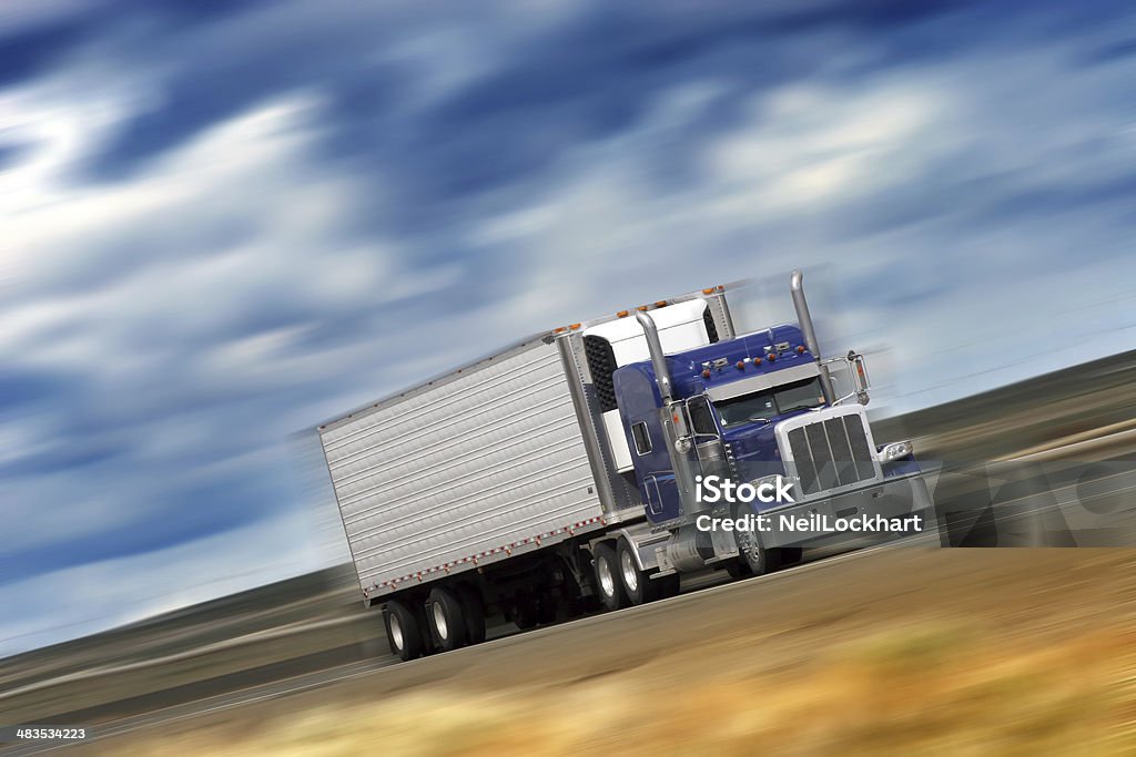 Speeding Big Rig Semi Truck Fast moving big rig semi truck with blurred background and blue sky and clouds. Activity Stock Photo