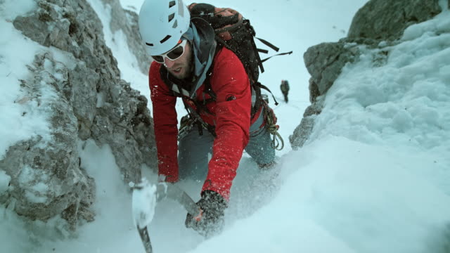 LD Winter climber using axe to ascend snow covered slope