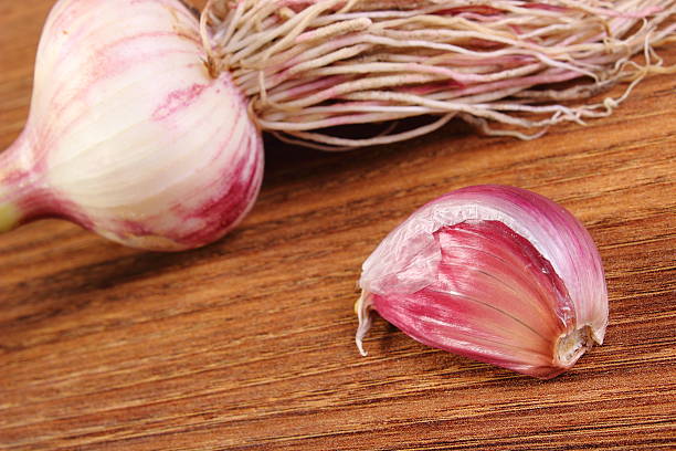 istock Whole garlic with roots and clove on wooden table 483539280