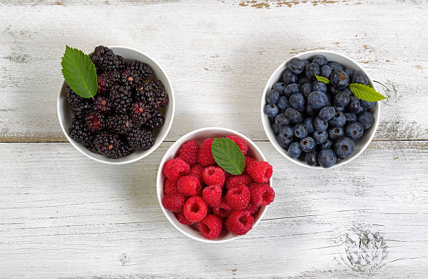 istock Bowls filled with freshly picked berries on rustic white wooden 483540014