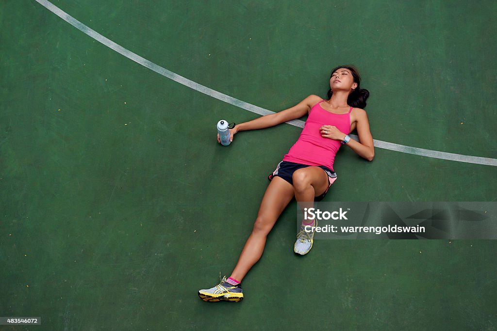 tired runner exhausted sporty woman runner laying on basketball court after fitness running workout outdoors Tired Stock Photo