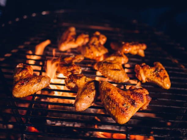 Spicy chicken wings grilling slowly over glowing coals at a night time barbecue