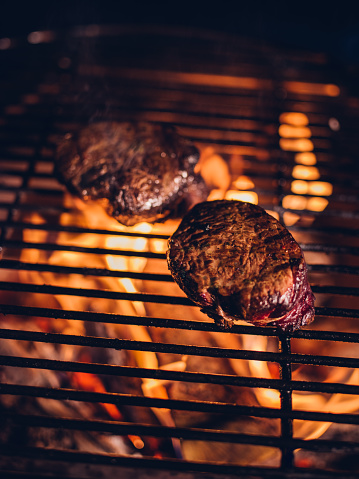 Two succulent beef steak medallions getting a flame-grill on a night time barbecue