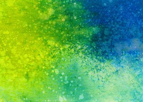 Hand painted abstract ink background with vibrant shades of blue and green. It has a mottled texture and paint splatters that would be great for a distressed look in a background design.