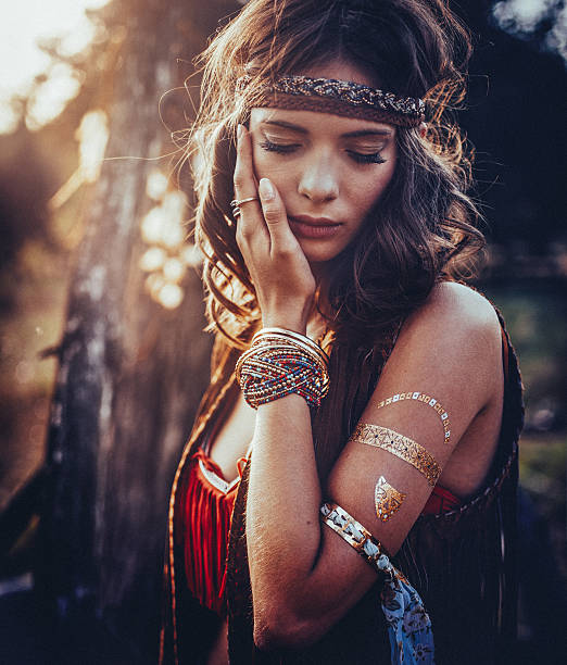 Hippie girl outdoors with jewelry and temporary gold foil tattoo Beautiful hippie girl standing outdoors with her eyes closed and wearing jewelry and a gold foil temporary tattoo vintage gold jewelry stock pictures, royalty-free photos & images