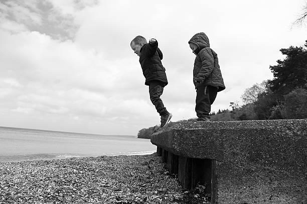 istock Boys jumping from wall onto beach 483555296