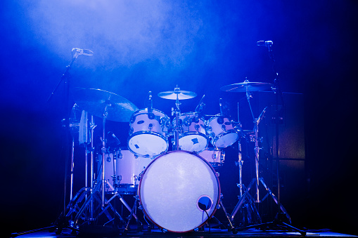 Full rock drum kit on stage with blue lighting and no drummer