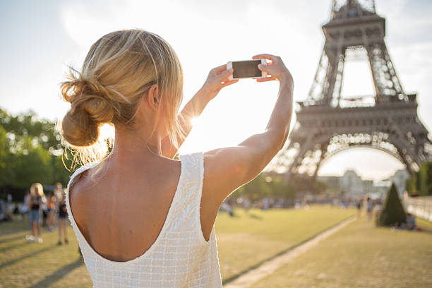 istock Cheerful woman photographing Eiffel tower using mobile phone 483561066