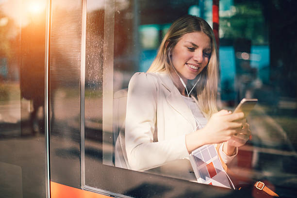 joven mujer escribiendo en su teléfono inteligente en el transporte público. - trolley bus fotografías e imágenes de stock
