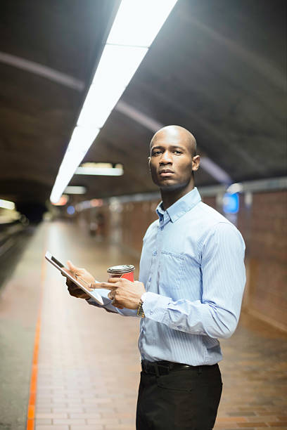 istock African man waiting for subway with tablet and coffee vertical 483562427