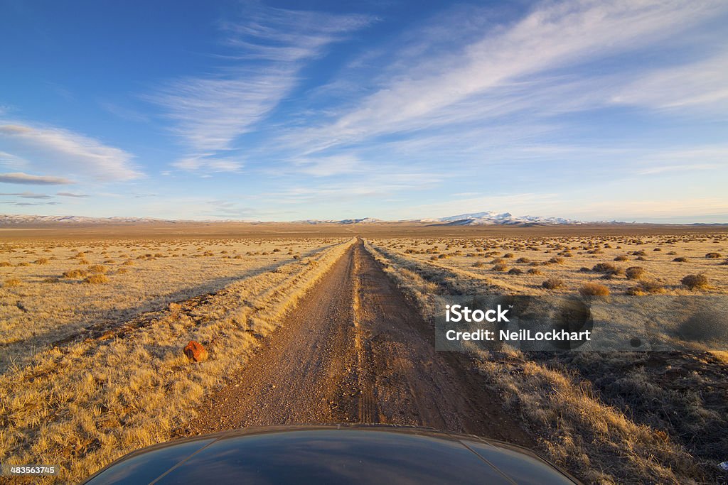 Nevada Desert Road Dirt road receeding into the distance.  Wide open spaces in the Nevada Desert with blue sky and clouds. Adventure Stock Photo