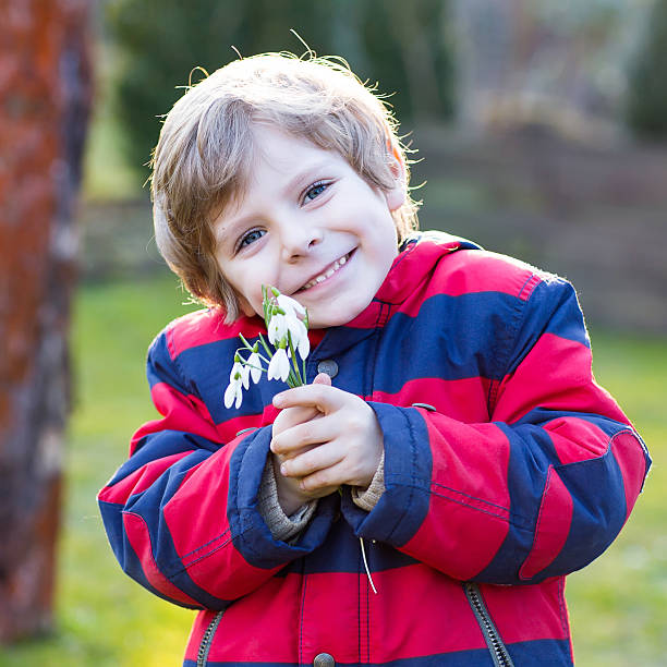 istock little kid boy in red jacket holding snowdrop flowers 483566324