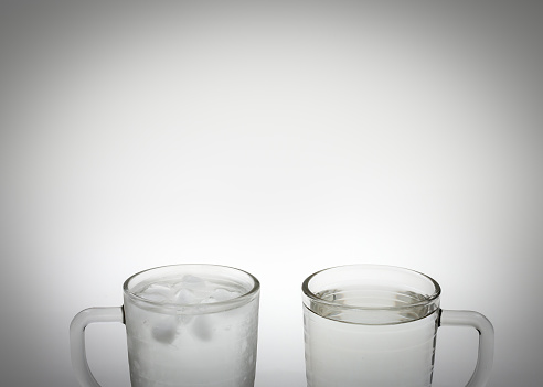 A glass of iced water sits next to a glass of warm water, begging the question: do you prefer iced water or warm?