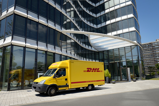 Düsseldorf, Germany - July 10, 2015: A DHL delivery truck in front of a modern office building.