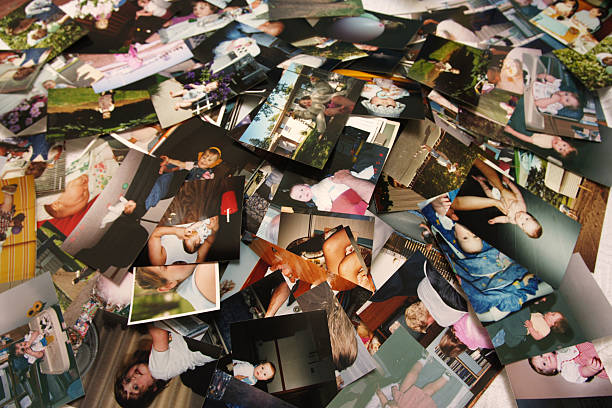 Unorganized pile of photographs of a little girl's life stock photo