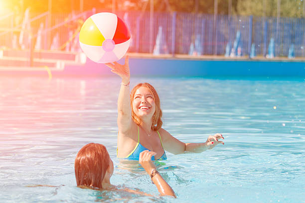 istock Two young women playing with ball on swimming pool 483572474