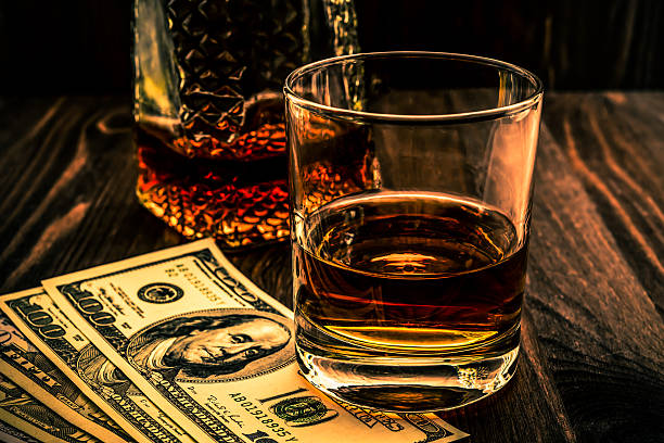 Glass of whiskey and dacanter with money