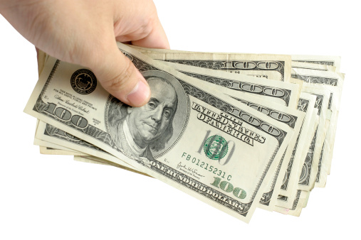Hand holding a stack of cash, against isolated white background. Clipping path included.